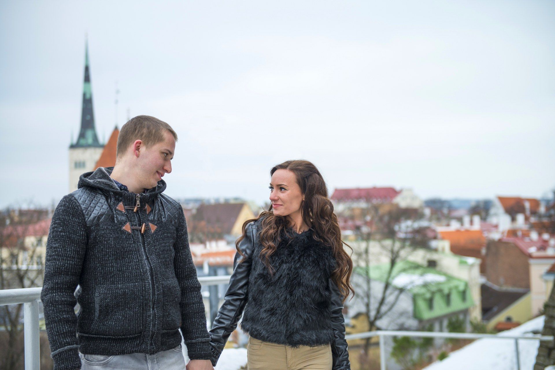 Una giovane coppia si tiene per mano sullo sfondo dei tetti del centro storico di Tallinn